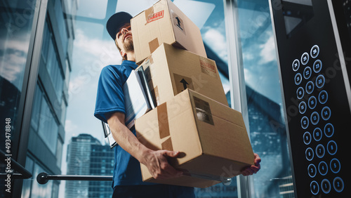 Young Delivery Person Riding Glass Elevator in Modern Office Building. Mail Courier Holding Cardboard Parcel Boxes. Handsome Mailman Delivering Fragile Packages in Business Center Lift. photo