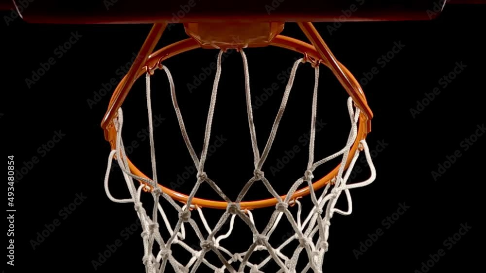 A low angle close-up view, directly under a basketball net and rim against a black background, as a free throw is nothing but net for the score. A low angle close-up view, directly under a basketball net and rim against a black background, as a free throw is nothing but net for the score.