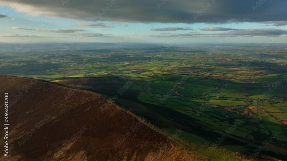 Mount Leinster, Carlow, Ireland, March 2022. Drone orbits Rathnageeragh hill facing west towards Garryhill with Corries Cross and Kilkenny in the distance at sunset. Mount Leinster, Carlow, Ireland, March 2022. Drone orbits Rathnageeragh hill facing west towards Garryhill with Corries Cross and Kilkenny in the distance at sunset.