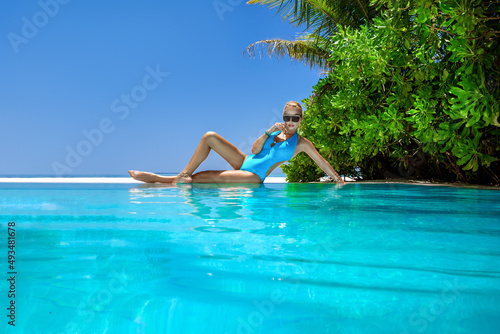 Sexy woman in bikini near the pool at Maldives tropical sand beach. Glamour model in elegant swimsuit near the pool. Perfect body bikini model. Bikini fashion. Luxury travel. Travel, tourism.
