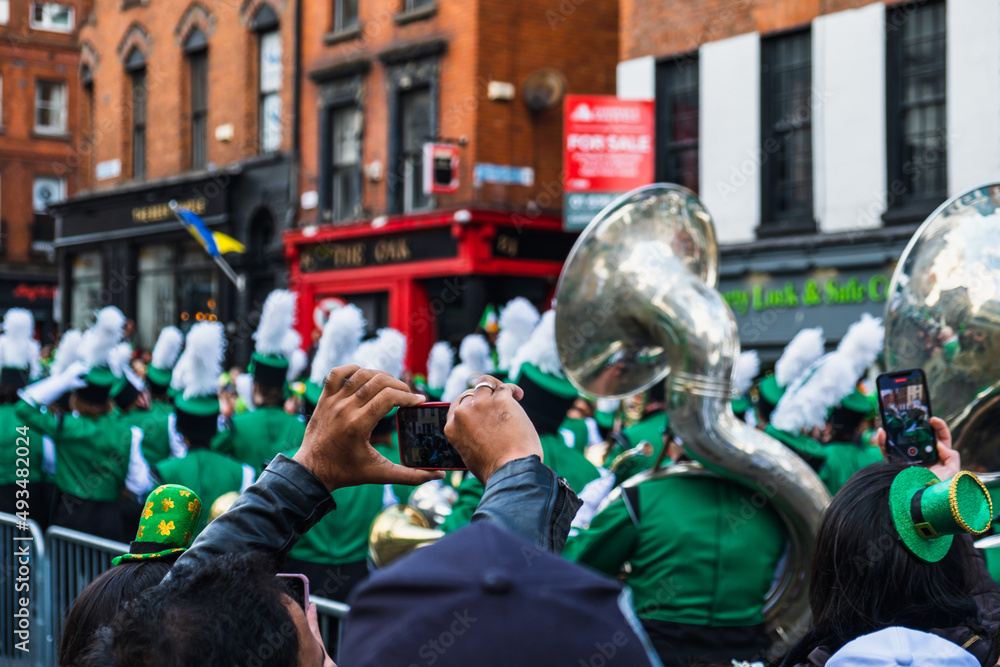 Person taking photos of the march, green hats in the crowd, the Saint Patrick's day parade in Dublin 2022, Ireland