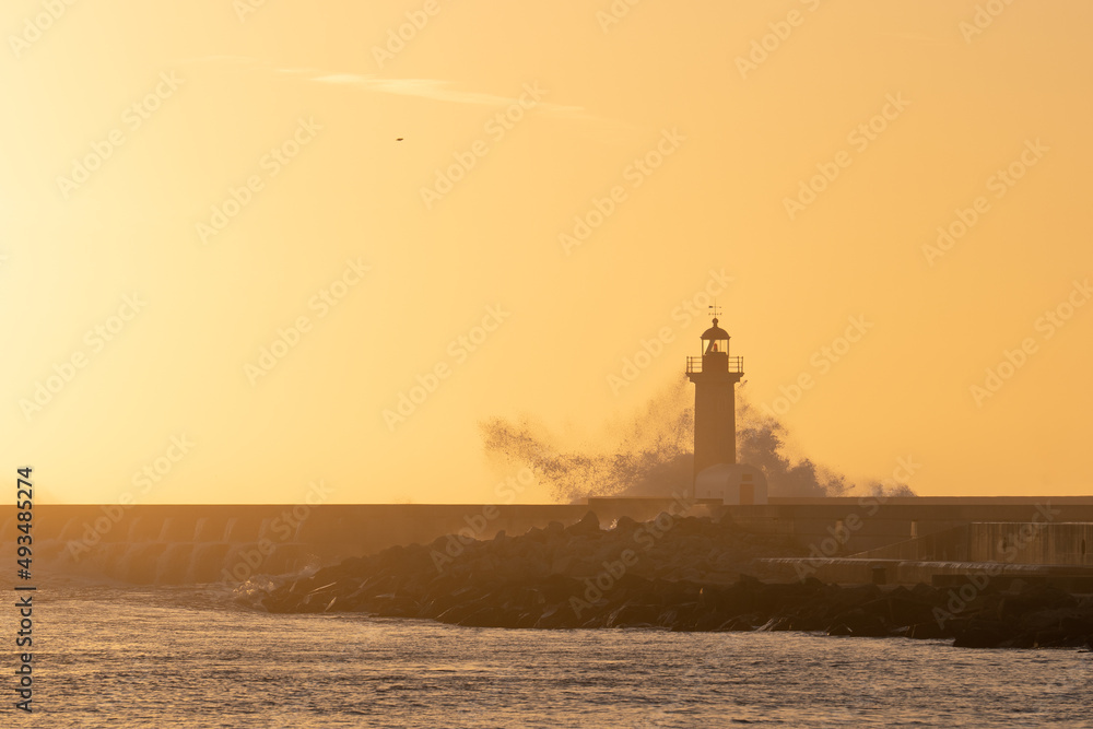 Beautiful view of a breakwater with a lighthouse at sunset.