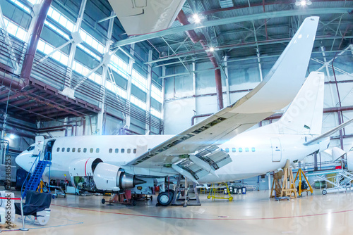 White passenger airliner in the hangar. Aircraft under maintenance. Checking mechanical systems for flight operations