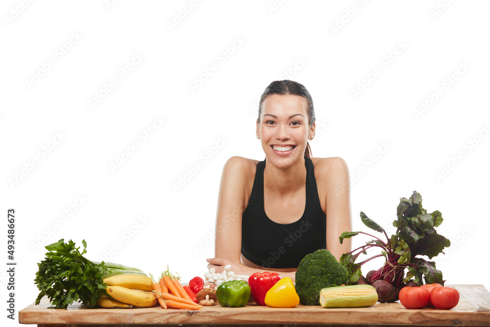 Its as fresh as it gets. Studio portrait of an attractive young woman posing with a table full of vegetables against a white background. Its as fresh as it gets. Studio portrait of an attractive young woman posing with a table full of vegetables against a white background.