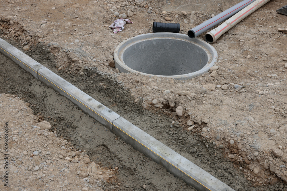 randstein schnurgerade und betonschacht mit kabelrohr auf baustelle im strassenbau