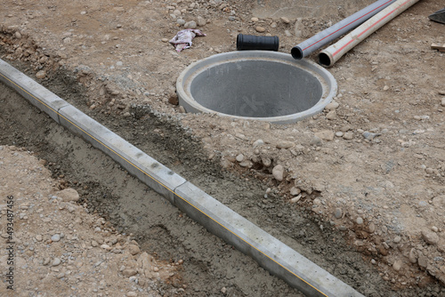 randstein schnurgerade und betonschacht mit kabelrohr auf baustelle im strassenbau