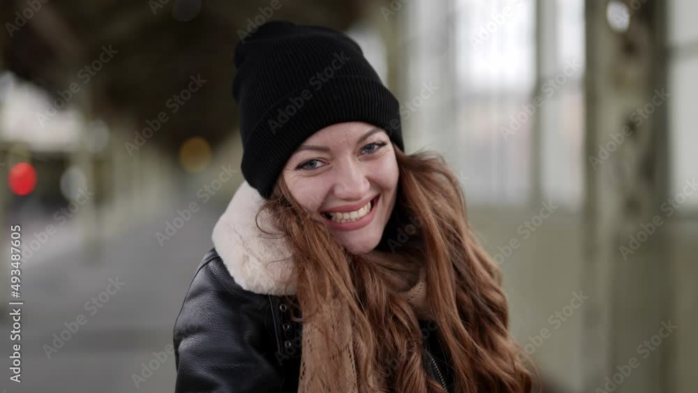 Smiling young woman in warm autumn clothes looks at the camera outside on the street feels like a happy lady portrait beautiful modern pretty slow motion Smiling young woman in warm autumn clothes looks at the camera outside on the street feels like a happy lady portrait beautiful modern pretty slow motion