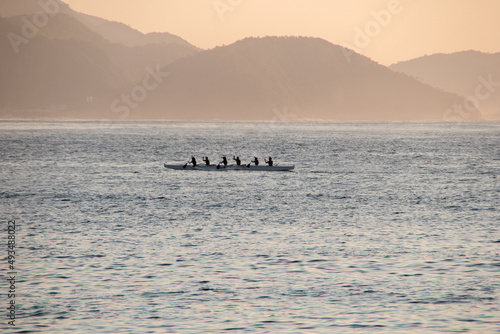 silhouette of people paddling a hawaiian canoe at Copacabana Beach in Rio de Janeiro.