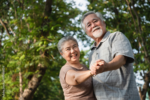 An elderly couple enjoys dancing and relaxing in the park with bright smiles and enjoys relaxing after retirement. Concept of exercise and leisure activities to relieve stress.