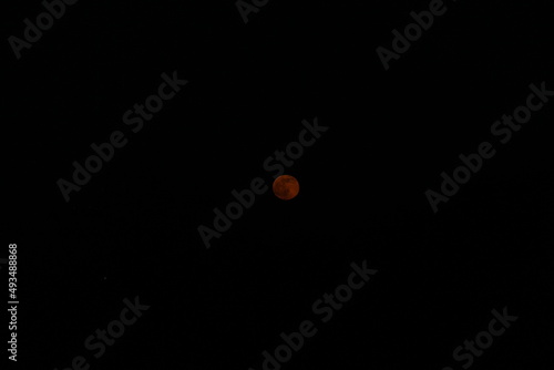 the moon has a reddish hue against a blue sky