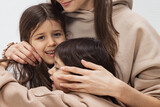 Happy loving family. Mother and her daughters sisters girl plays and hugs. Girls portrait indoors