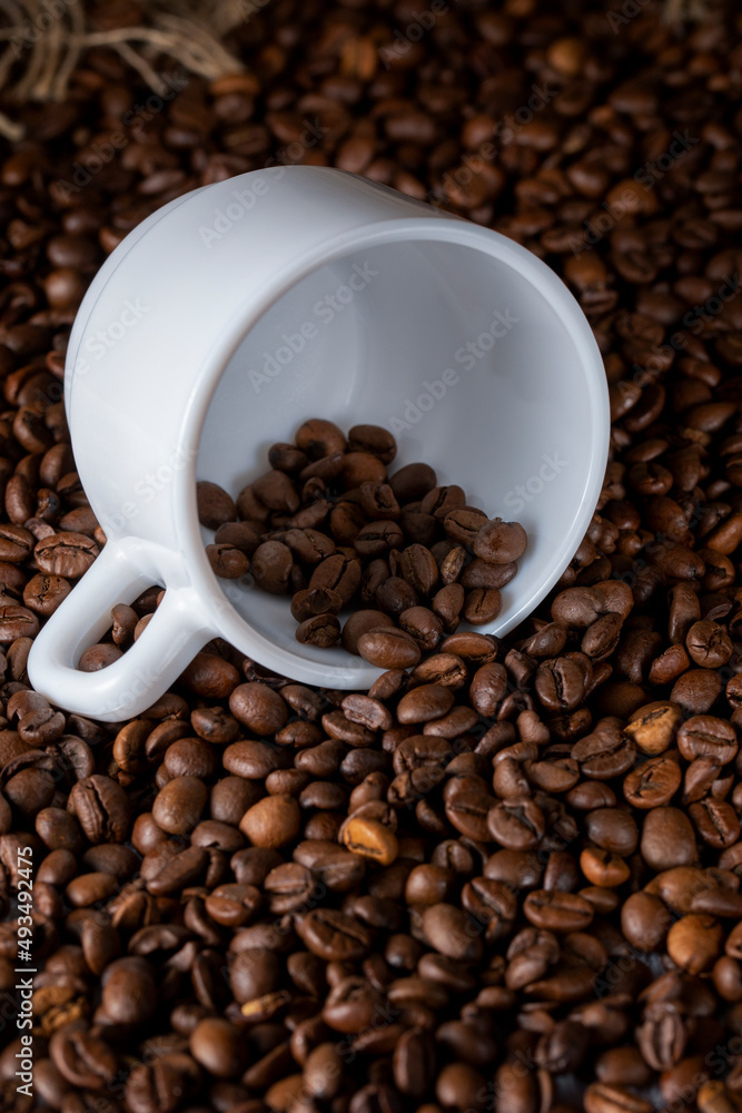 Fototapeta premium Roasted coffee beans and white ceramic cup on the table