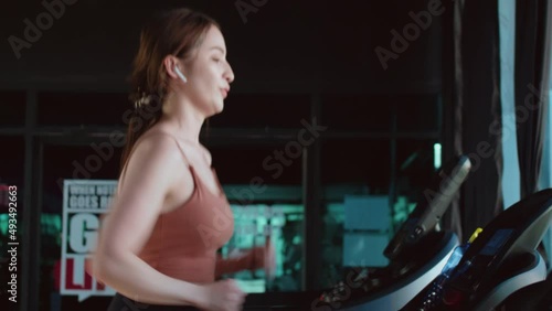 Asian fit girl running on treadmill at fitness gym center.Healthy and running concept. Smiling active young Asian woman running on treadmill.