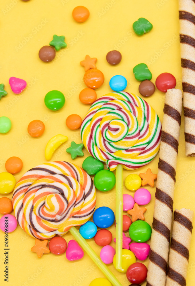 Colorful different kinds of candies isolated on yellow background
