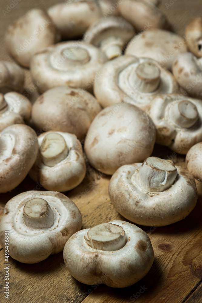 Champignons on a wooden background. Fresh white mushrooms. A lot of mushrooms Champignons on a wooden background. Fresh white mushrooms. A lot of mushrooms