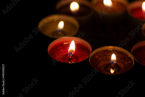 Round candles burn in dark. Wax candles on dark background. Red and yellow lights.