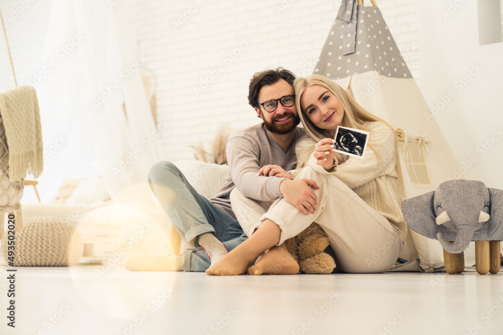 lovely caucasian couple sitting together and showing a ultrasound photo of their unborn baby. High quality photo lovely caucasian couple sitting together and showing a ultrasound photo of their unborn baby. High quality photo