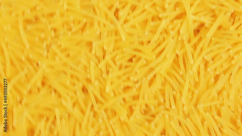 Background of Uncooked Noodles that Slowly Moving Down - Top View. Raw Pasta in Move. Texture of Dry Vermicelli Background of Uncooked Noodles that Slowly Moving Down - Top View. Raw Pasta in Move. Texture of Dry Vermicelli