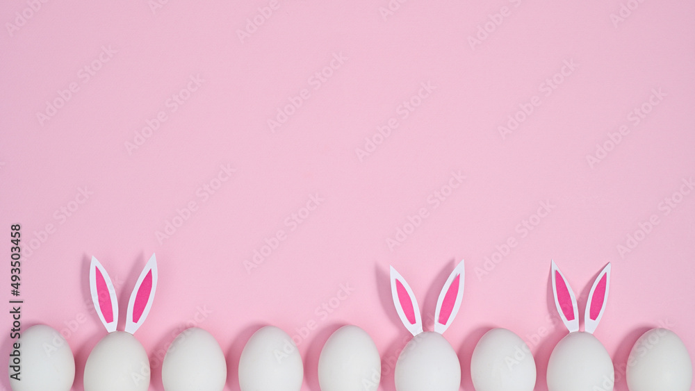 Creative Easter copy space background with eggs with bunny ears on pastel pink theme. Flat lay