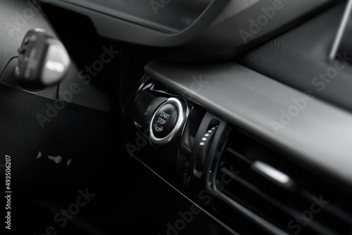 Engine start button close up. Starting or stopping the car engine without a key. The concept of the ignition system. Premium luxury SUV elements. Black interior of a modern business class car.