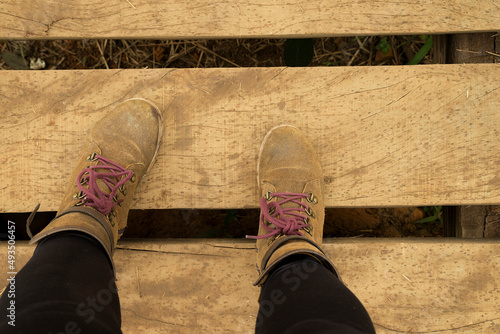 Pés calçados com botas de couro pisando um superfície de tabuas de madeira. photo