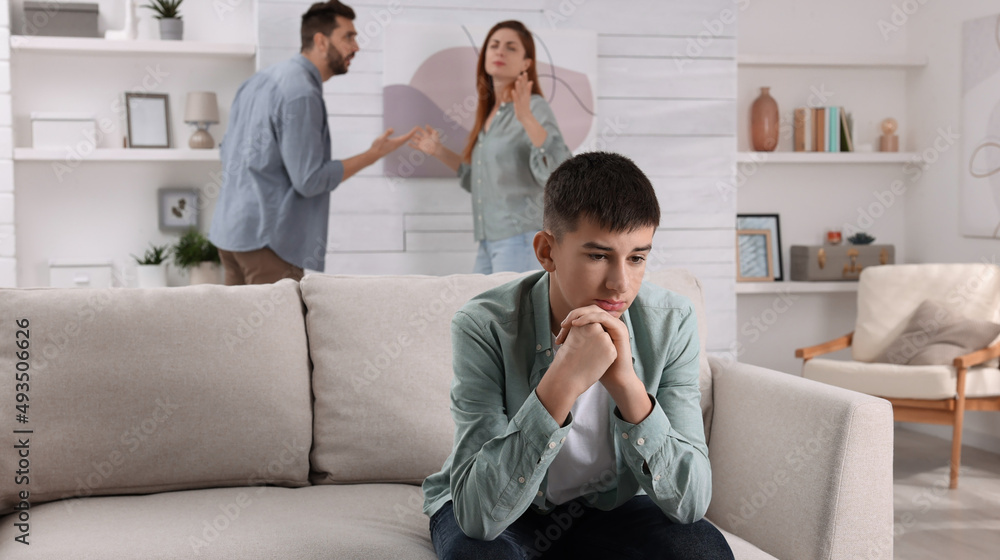 Couple arguing at home, focus on their unhappy teenage boy. Problems in family Couple arguing at home, focus on their unhappy teenage boy. Problems in family