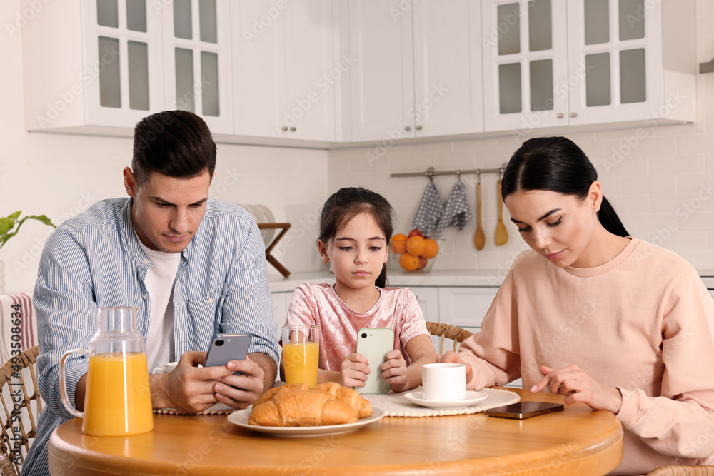 Internet addiction. Family with smartphones at table in kitchen Internet addiction. Family with smartphones at table in kitchen