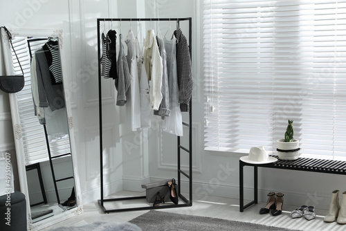 Rack with stylish women's clothes and large mirror in dressing room. Interior design © New Africa