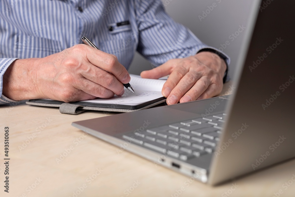 Man taking notes in planner and using laptop for online education, distant work. Hands closeup. Man writing schedule, thoughts, important information. High quality photo Man taking notes in planner and using laptop for online education, distant work. Hands closeup. Man writing schedule, thoughts, important information. High quality photo