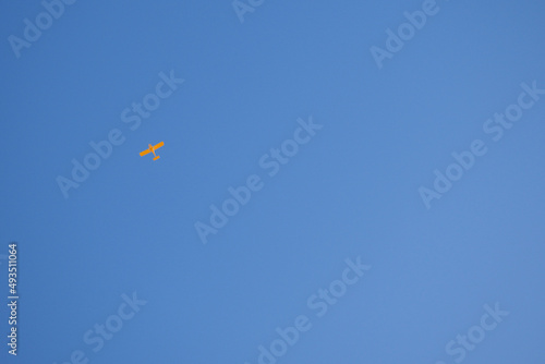 Light aircraft flies in the clear blue sky. Background or backdrop. Yellow small plane. General aviation. Air sports and tourism
