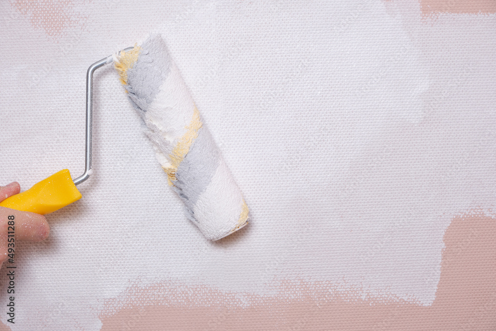 Obraz premium Painting the walls with a paint roller pink with white paint, home repairs.
