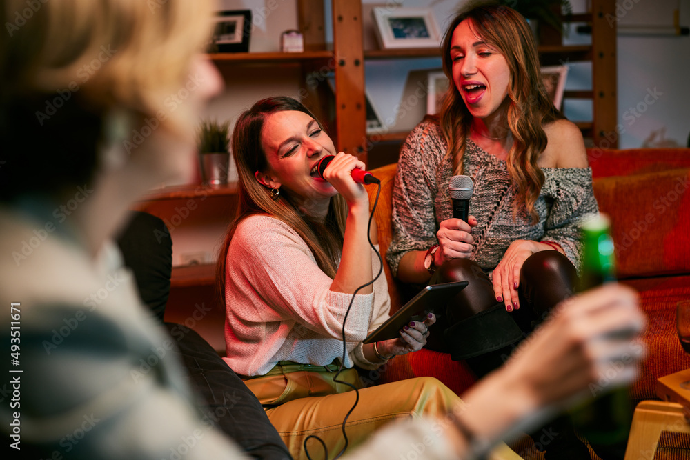 Fototapeta premium Girls having fun at karaoke night at home.