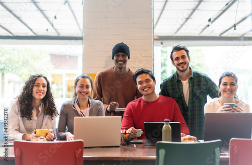 Smiling multiethnic coworkers looking at camera making team picture in modern office together - Happy diverse work group or department laugh posing for photo at workplace - Show unity and cooperation