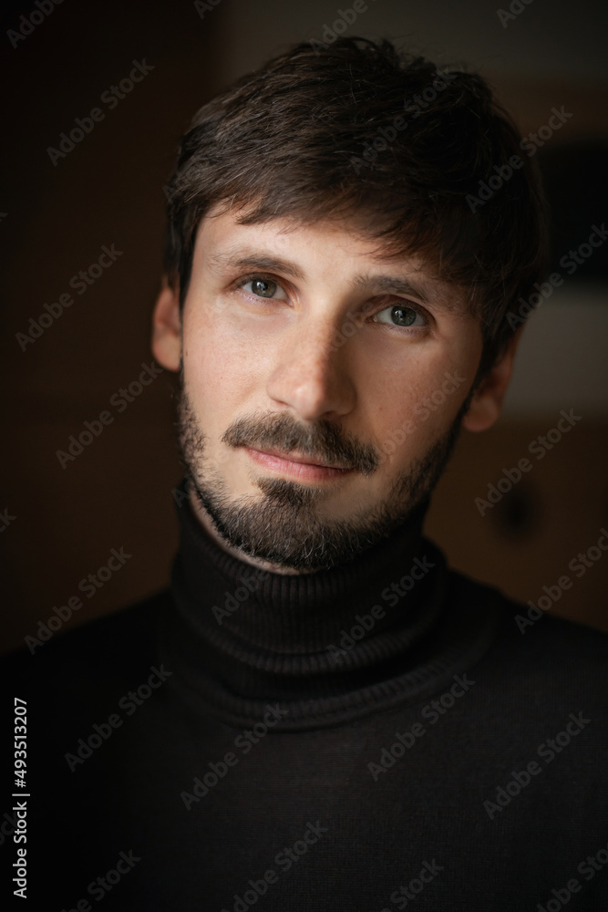 Fototapeta premium Expressive close-up portrait of a man with a beard. natural light. dark background