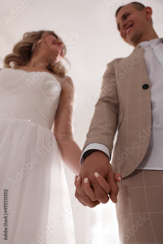 Fototapeta Naklejka Na Ścianę i Meble -  Bride and groom holding hands together, low angle view