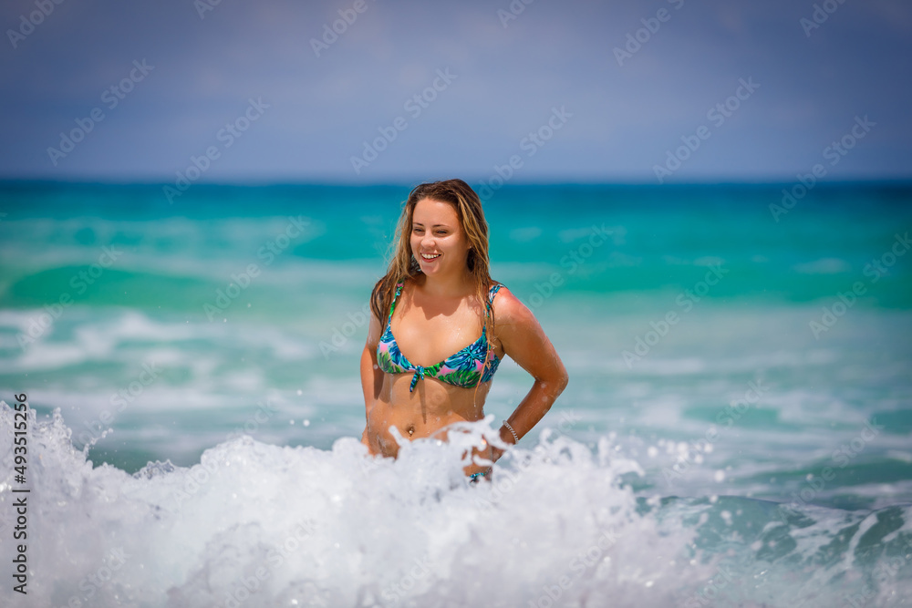 A young girl in a green bathing suit bathes in the sea and laughs. High quality photo