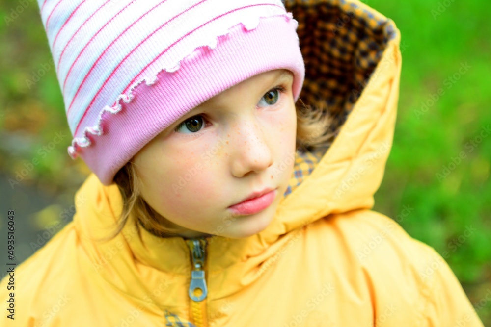 Little Girl in the spring he builds different faces in a yellow jacket against the background of spring flowering High quality photo Little Girl in the spring he builds different faces in a yellow jacket against the background of spring flowering High quality photo
