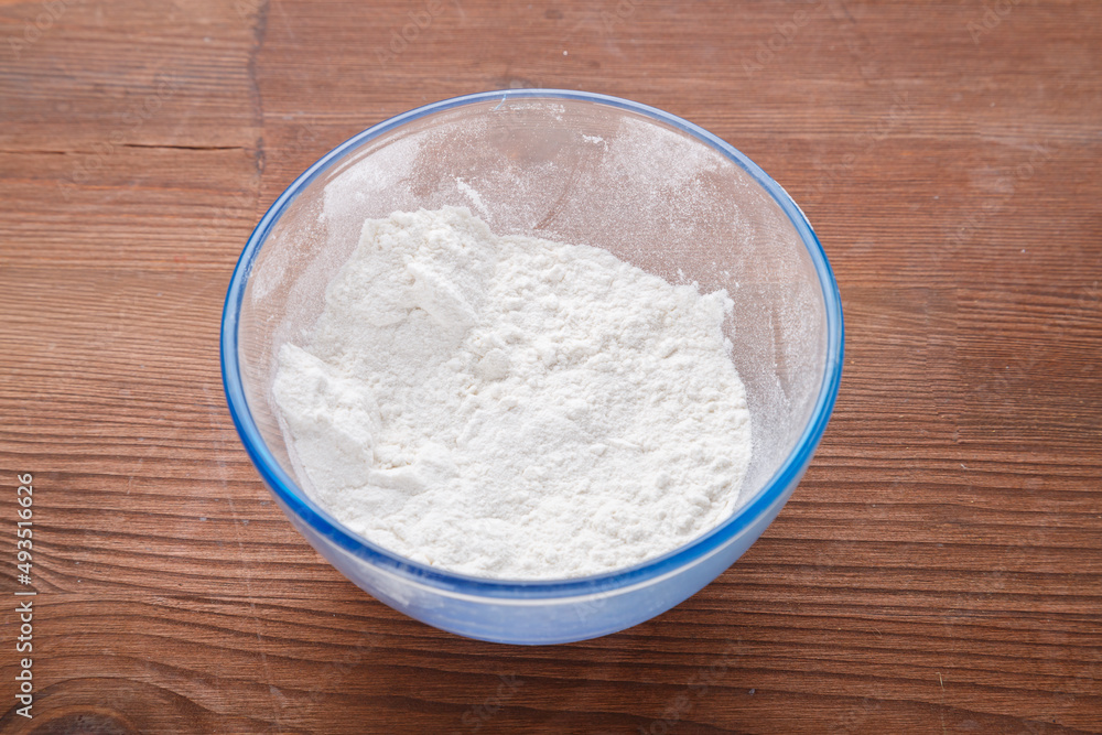 Confectionery flour in a bowl on a wooden table. Confectionery flour in a bowl on a wooden table.
