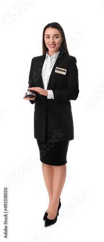 Happy young receptionist in uniform holding service bell on white background