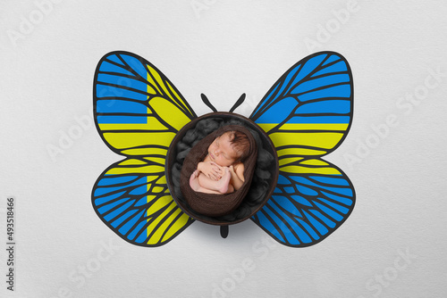 Tiny baby portrait with wings in color of national flag. Newborn photography concept. Sweden