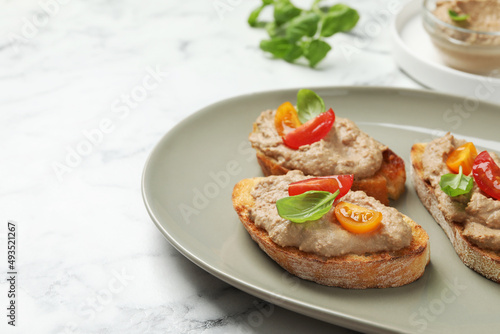 Slices of bread with delicious pate, tomatoes and basil on white marble table, closeup. Space for text