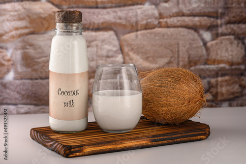 NO LOGO. NO TRADEMARK. Coconut milk bottle and glass on background of coconut