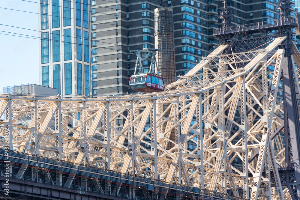 Fototapeta premium Roosevelt Island Tramway runs beside the Queensboro Bridge toward the high-rise residential building in Midtown Manhattan from Roosevelt Island on November 2021 New York City NY USA. 