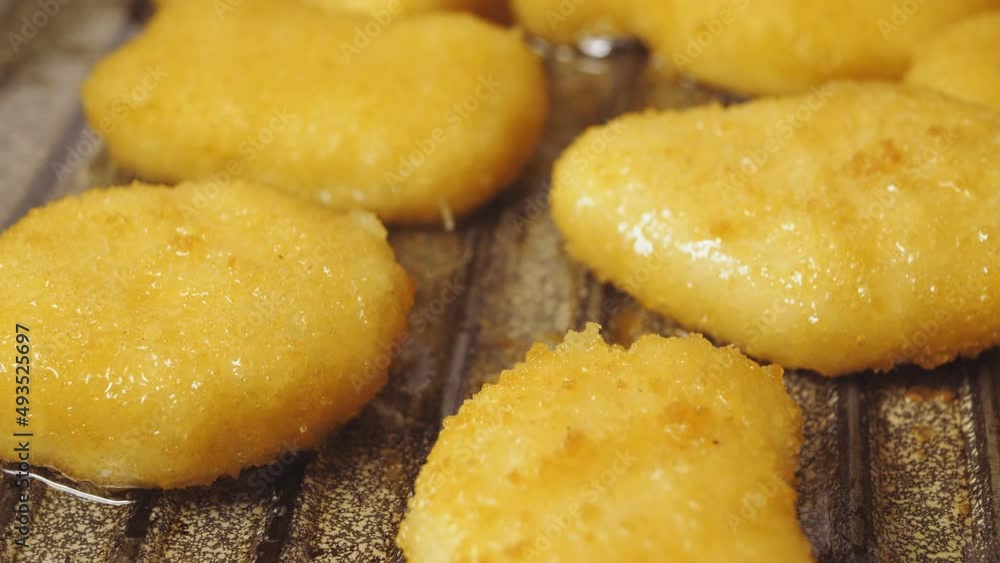 Breaded chicken nuggets are fried in a pan in oil. Breaded chicken nuggets are fried in a pan in oil.