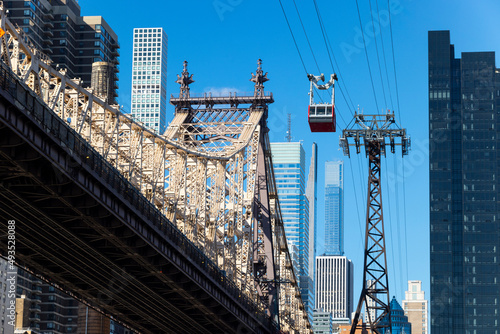 Roosevelt Island Tramway runs beside the Queensboro Bridge toward the high-rise residential building in Midtown Manhattan from Roosevelt Island on November 2021 New York City NY USA.
 photo