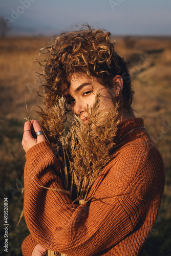 A mysterious portrait of a beautiful young woman with curly hair while enjoying the sun