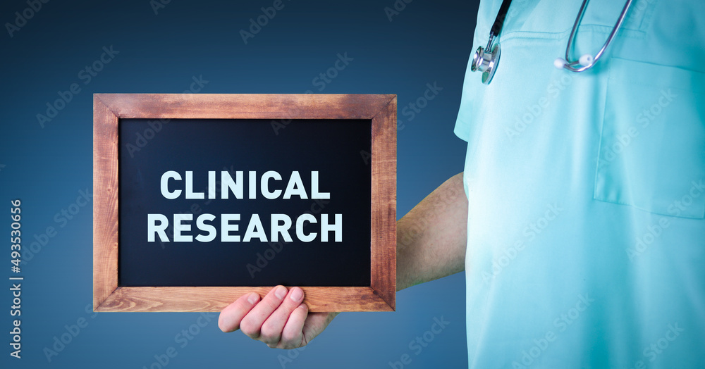 Clinical research. Doctor shows sign/board with wooden frame. Background blue Clinical research. Doctor shows sign/board with wooden frame. Background blue