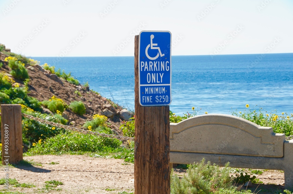 Handicap parking sign on beach parking lot with Pacific ocean in