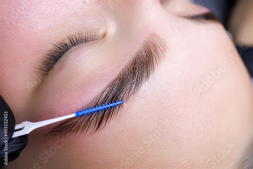 Photo combing the hairs in the eyebrows with a brush after the procedure of coloring a