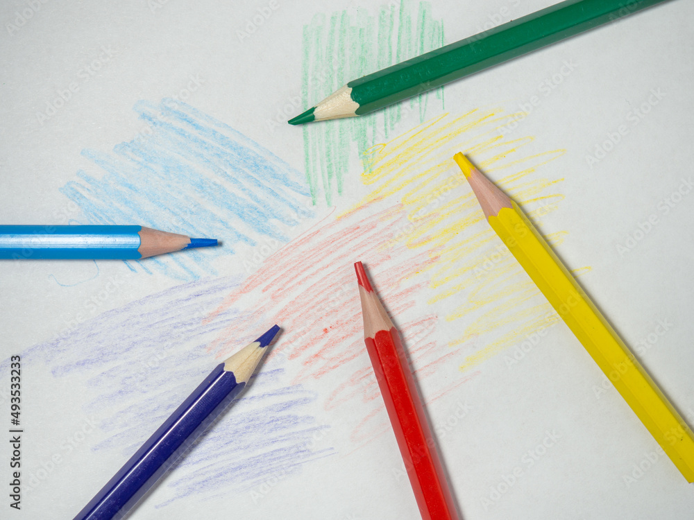 Colored wooden pencils on paper. Sharpened pencils. Drawing tool. Accessories for creativity. Colored wooden pencils on paper. Sharpened pencils. Drawing tool. Accessories for creativity.